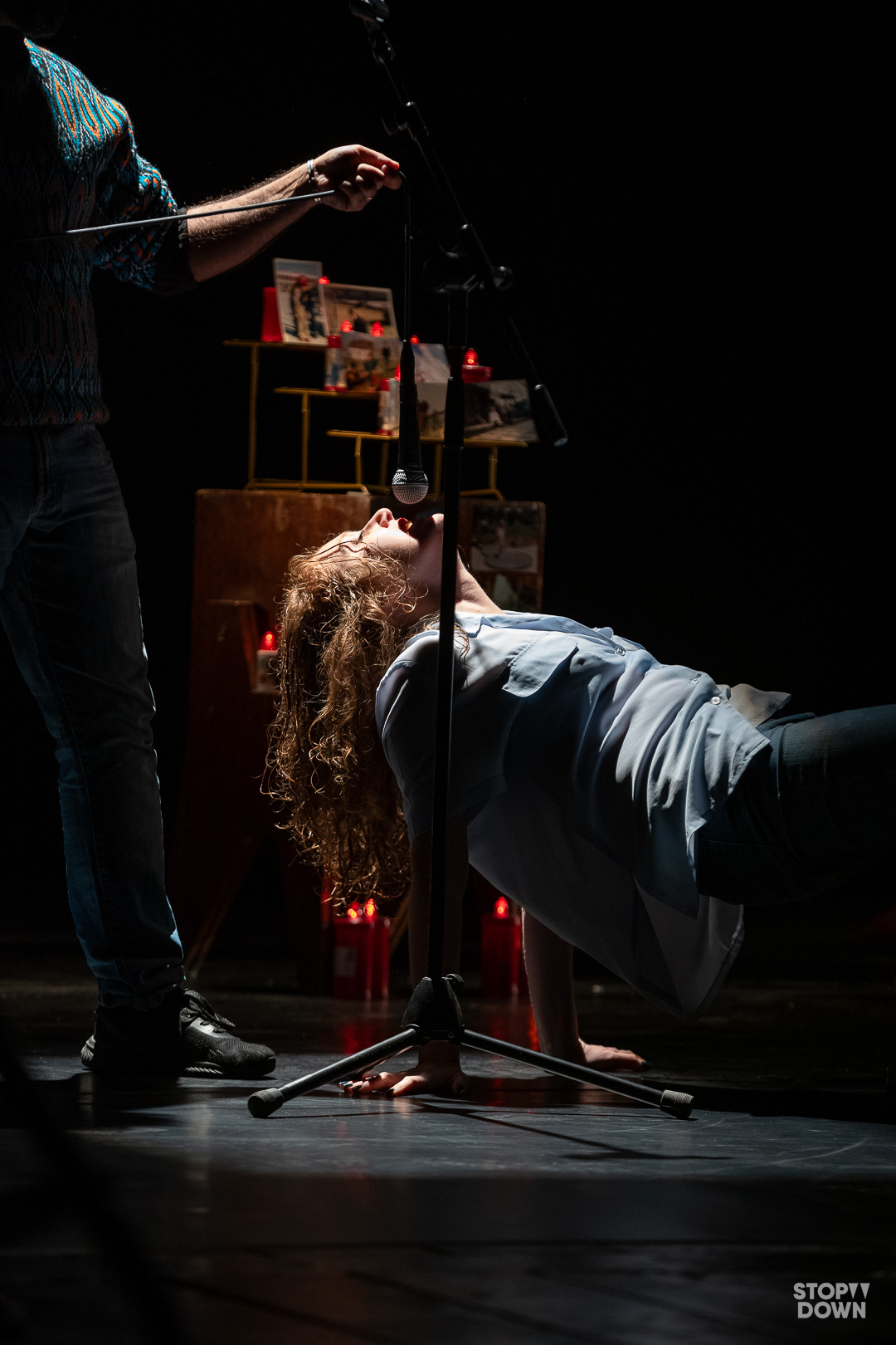 Stefania Tagliaferri attrice e regista recita sul palco un monologo rivolta verso l'alto, mentre un attore sorregge il microfono dall'alto. sullo sfondo un altarino con ceri e fotografie. Ph Giorgio Prodoti