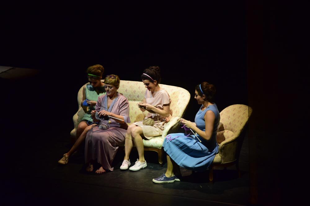 In scena sul palco di Donne che si vogliono sposare. Forse sedute su un divano chiaro recitano sferruzzando Mariachiara Caneparo, Sauvage Rolla e Francesca Zanin. Giulia Sartore chiude la composizione seduta su una poltrona affiancata sulla destra.