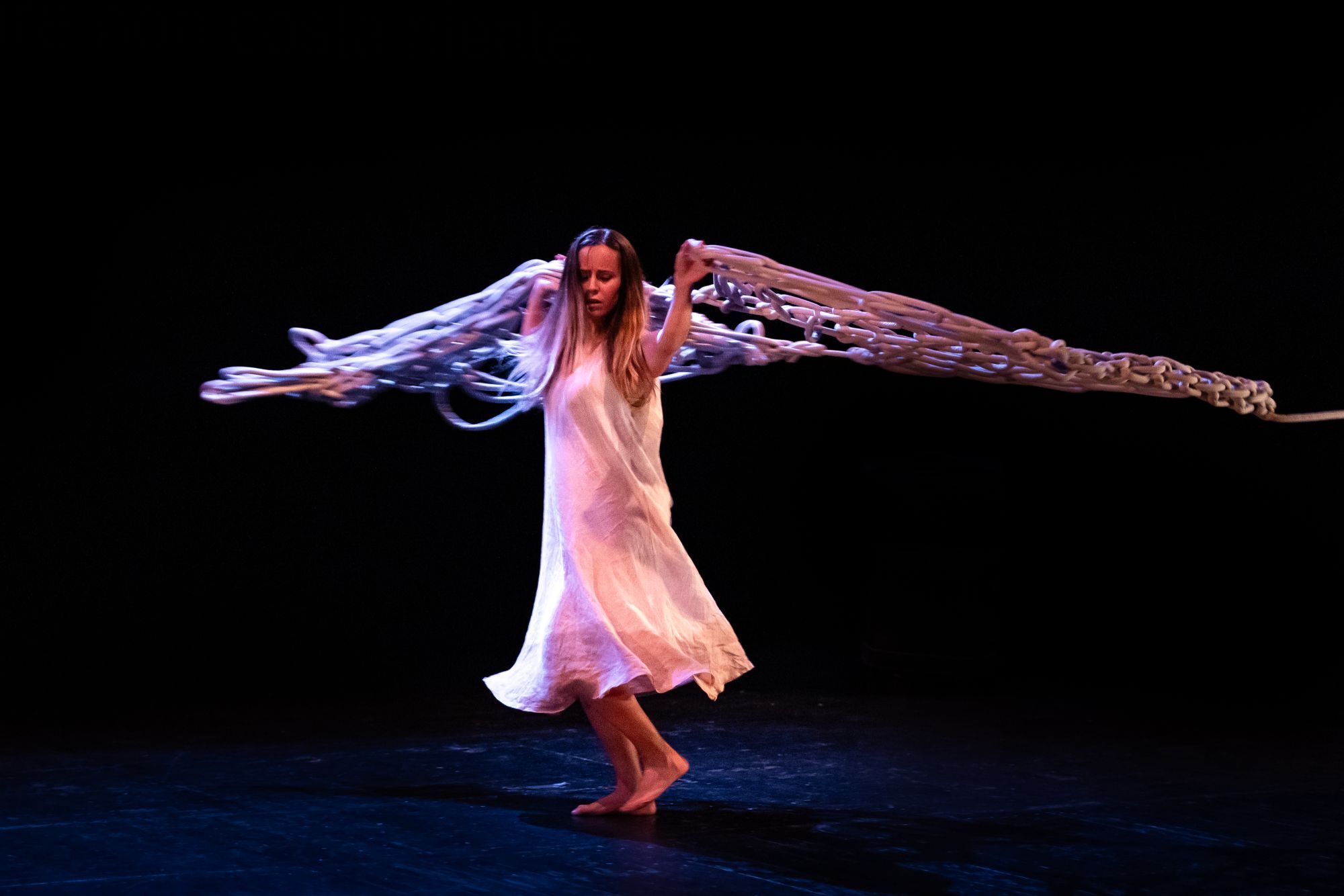 Eleonora Cicconi attrice si muove sul palco sollevando un elemento di scena dapprima gomitolo e qui nello specifico evocativo delle vele di una nave, nello spettacolo Tinta una storia autobiografica