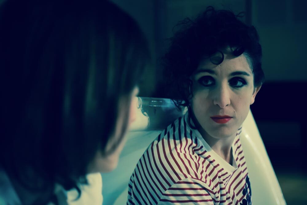 Primo piano di Alice Corni attrice mentre volge uno sguardo intenso a Elisa Zanotto, attice, rivolta di spalle a chi osserva lo scatto fotografico. Sono in scena in Apnea. La più giovane delle parche, spettacolo di Palinodie.